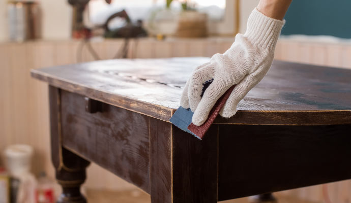 professional worker sanding the edge of a wooden table