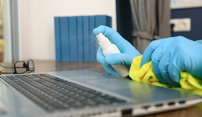 Person cleaning a Laptop with spray bottle