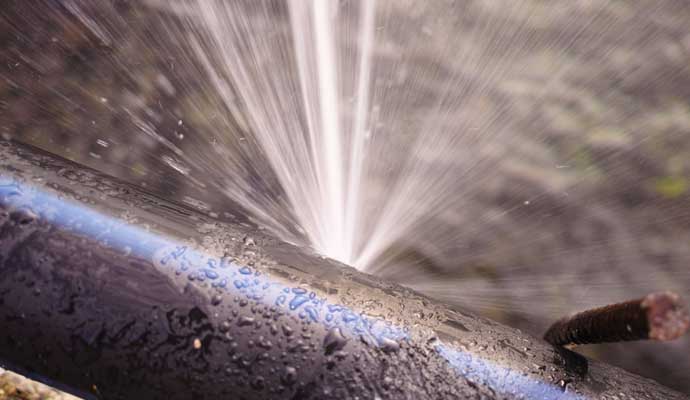 Close-up view of a burst water pipe with water gushing out