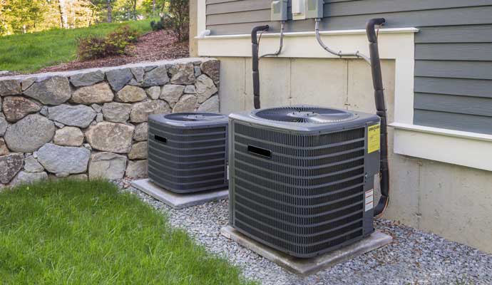 Two outdoor HVAC units installed beside a house